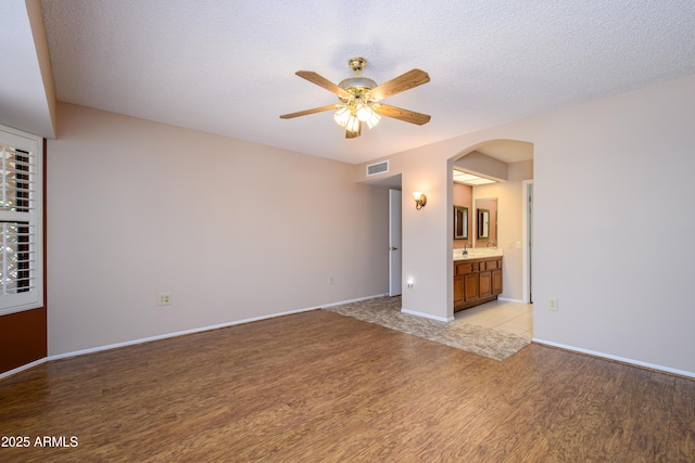 13721 W Franciscan Dr, Sun City West, AZ 85375 - unfurnished room featuring light wood-style flooring, ceiling fan, arched walkways, a sink, and baseboards