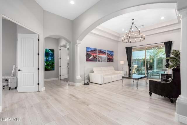 living room featuring light wood-type flooring, decorative columns, and a chandelier