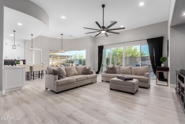 living room with ceiling fan with notable chandelier and light hardwood / wood-style flooring