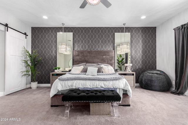 bedroom with ceiling fan, carpet floors, and a barn door