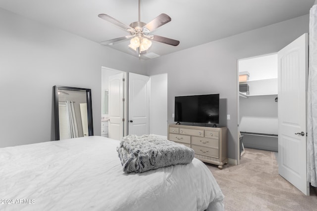 bedroom with a spacious closet, connected bathroom, a closet, ceiling fan, and light colored carpet