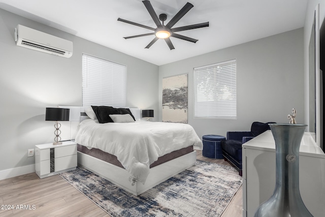 bedroom with light wood-type flooring, an AC wall unit, and ceiling fan