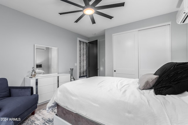 bedroom featuring a wall mounted AC, ceiling fan, a closet, and hardwood / wood-style flooring