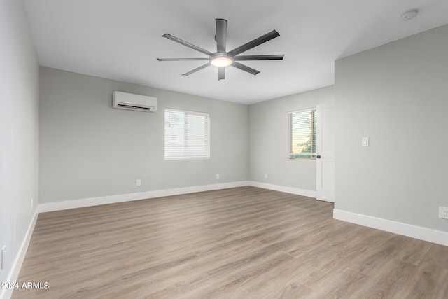 unfurnished room featuring ceiling fan, a wall unit AC, light hardwood / wood-style floors, and a healthy amount of sunlight