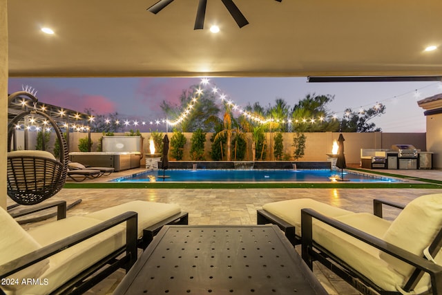 pool at dusk with pool water feature, a patio, and area for grilling