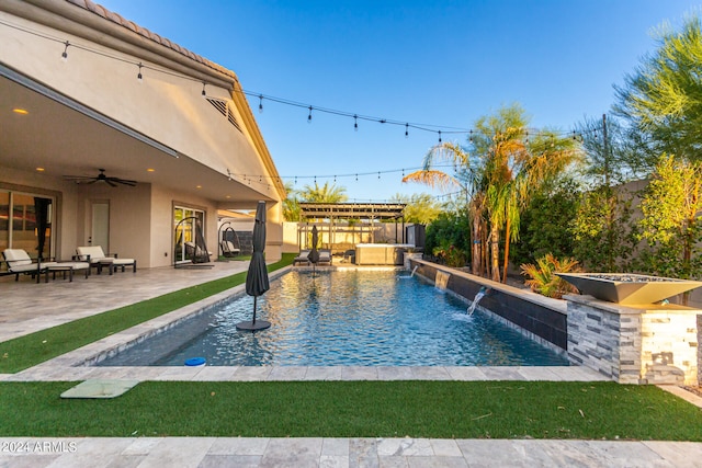 view of swimming pool with ceiling fan, an outdoor kitchen, a patio area, and pool water feature