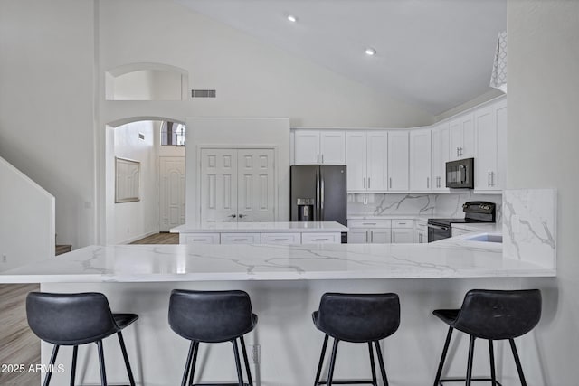 11257 E Reginald Ave, Mesa, AZ 85212 - kitchen with black appliances, a peninsula, a center island, tasteful backsplash, and white cabinets