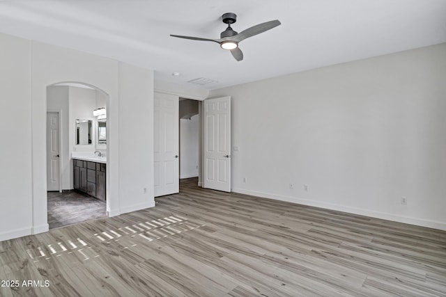 11257 E Reginald Ave, Mesa, AZ 85212 - unfurnished bedroom featuring light wood finished floors, arched walkways, ensuite bathroom, and a ceiling fan