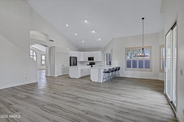 11257 E Reginald Ave, Mesa, AZ 85212 - kitchen with stainless steel microwave, open floor plan, high vaulted ceiling, refrigerator with ice dispenser, and a kitchen breakfast bar