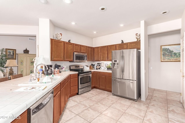 kitchen featuring tile counters, light tile patterned flooring, sink, and appliances with stainless steel finishes