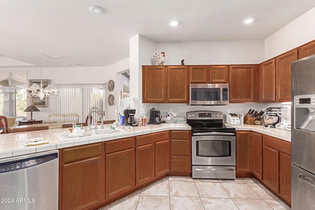 kitchen featuring tile countertops, stainless steel appliances, a notable chandelier, and sink