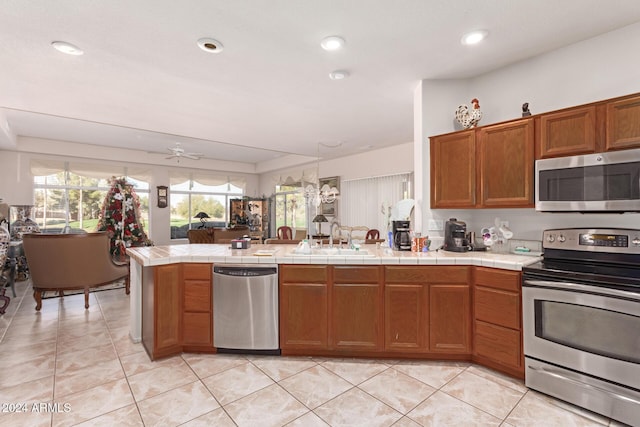 kitchen with tile countertops, sink, ceiling fan, kitchen peninsula, and stainless steel appliances