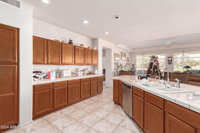 kitchen featuring ceiling fan, tile counters, sink, stainless steel dishwasher, and light tile patterned flooring