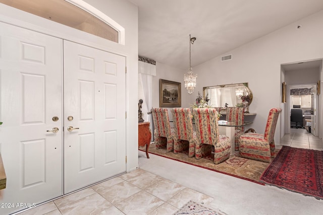 carpeted entryway featuring lofted ceiling and a chandelier