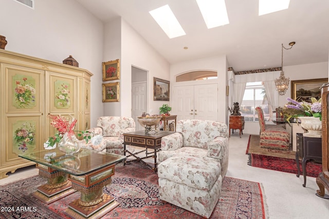 carpeted living room with a skylight, high vaulted ceiling, and a notable chandelier