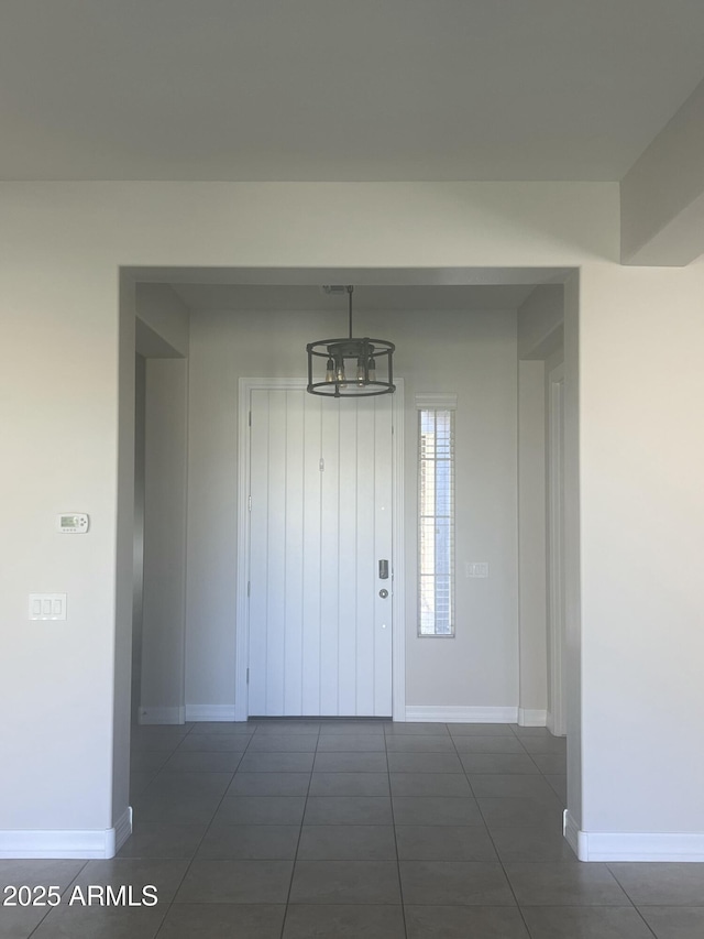 foyer with dark tile patterned floors and a chandelier