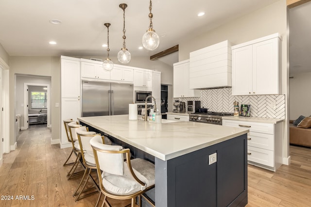 kitchen featuring built in appliances, vaulted ceiling, and light wood-type flooring