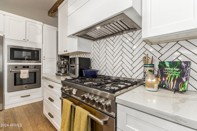 kitchen featuring premium range hood, white cabinetry, high end stainless steel range, light hardwood / wood-style flooring, and light stone counters