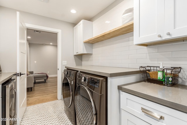 laundry area featuring light hardwood / wood-style flooring, independent washer and dryer, wine cooler, and cabinets