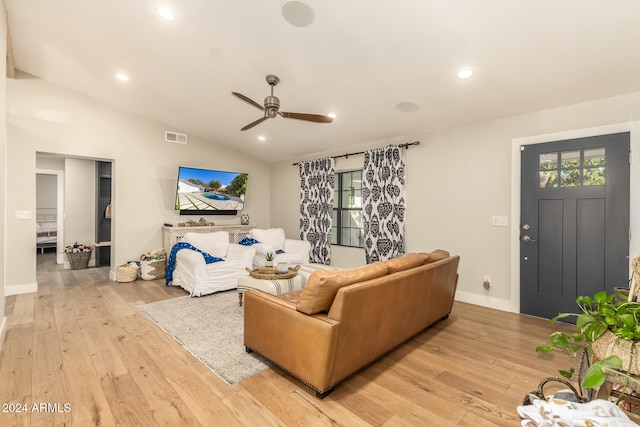 living room with ceiling fan, vaulted ceiling, and light wood-type flooring