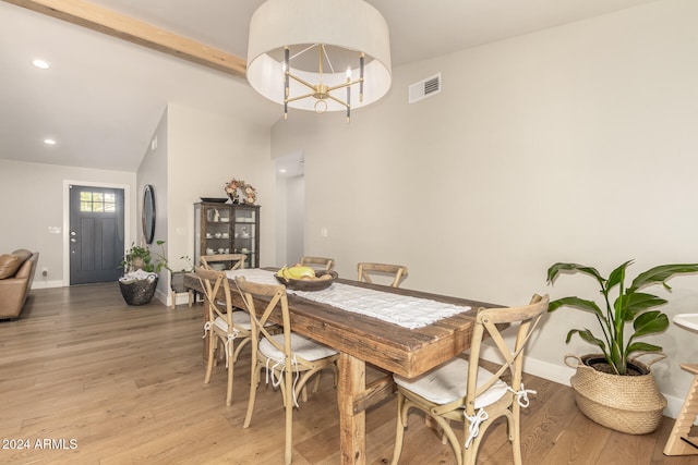 dining space with an inviting chandelier, light hardwood / wood-style flooring, and lofted ceiling