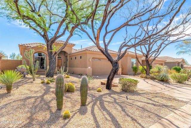 mediterranean / spanish-style home featuring a tiled roof, stucco siding, a garage, and concrete driveway