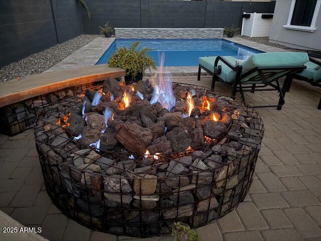 view of swimming pool with a patio and a fire pit