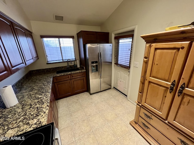 kitchen with light tile patterned flooring, sink, vaulted ceiling, appliances with stainless steel finishes, and dark stone counters