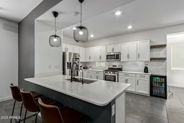 kitchen with appliances with stainless steel finishes, pendant lighting, sink, white cabinets, and kitchen peninsula