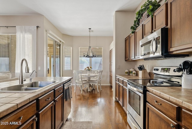 kitchen featuring appliances with stainless steel finishes, sink, tile counters, and decorative light fixtures