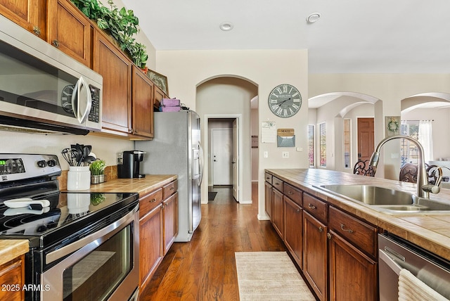 kitchen with appliances with stainless steel finishes, sink, and dark hardwood / wood-style floors