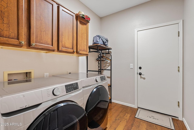 laundry area featuring dark wood-type flooring, washer and clothes dryer, and cabinets