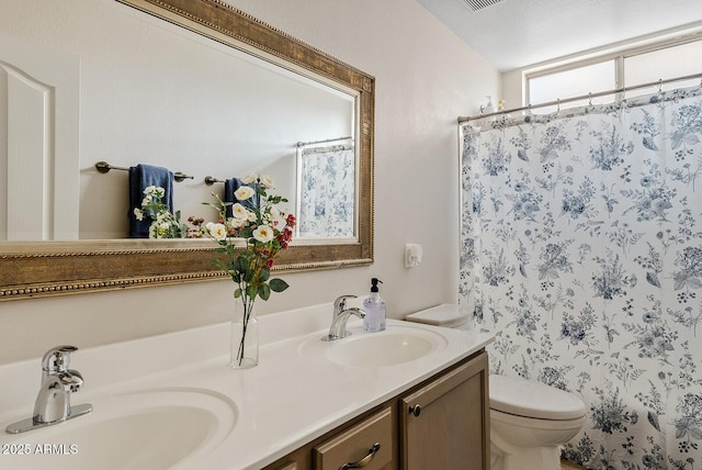 bathroom featuring vanity, walk in shower, and toilet