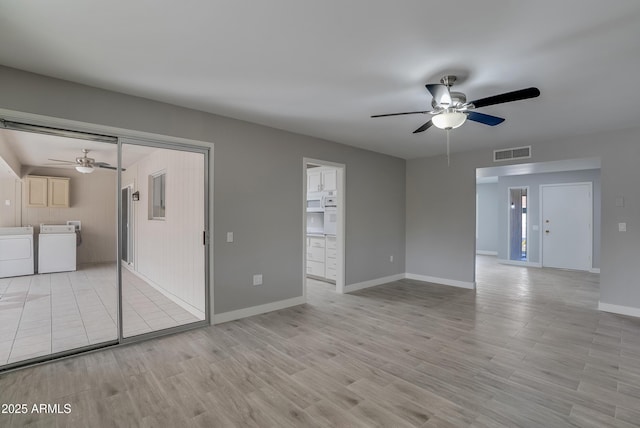 unfurnished room with visible vents, baseboards, ceiling fan, light wood-type flooring, and washing machine and dryer