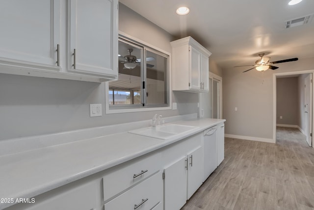 kitchen featuring light countertops, a ceiling fan, white cabinets, white dishwasher, and a sink