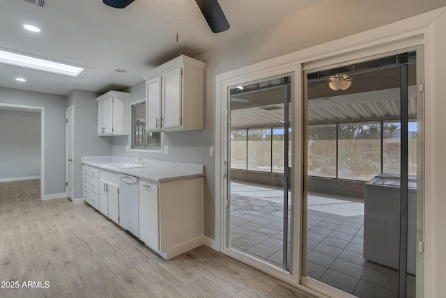 kitchen featuring a ceiling fan, light countertops, light wood-type flooring, white cabinetry, and a sink