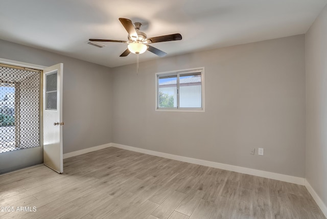 empty room with visible vents, light wood-style flooring, and baseboards