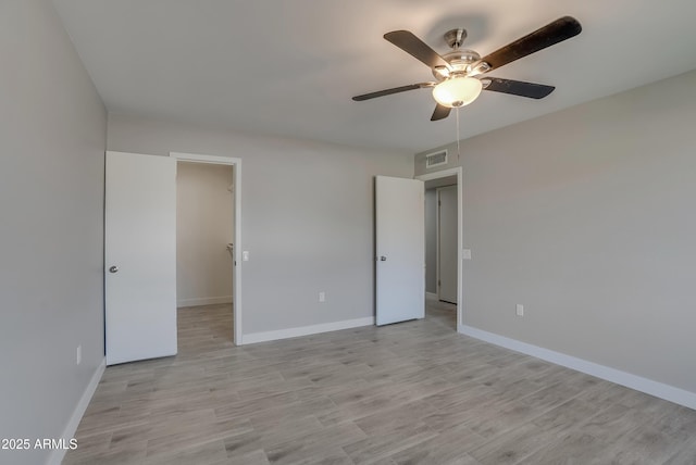 unfurnished bedroom featuring light wood-style flooring, visible vents, ceiling fan, and baseboards