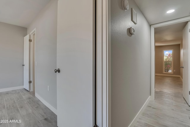 corridor featuring light wood-type flooring and baseboards