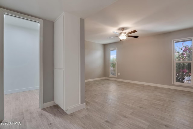 spare room featuring light wood-style flooring, baseboards, and a ceiling fan