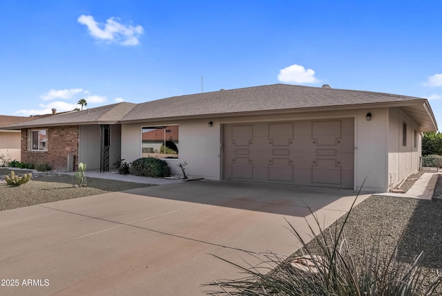 single story home with driveway, roof with shingles, a garage, and brick siding