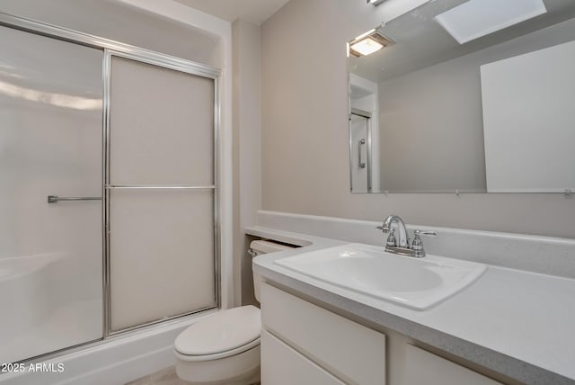 bathroom with toilet, vanity, and a shower with shower door