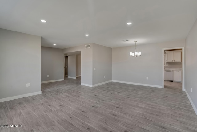 empty room with a notable chandelier, recessed lighting, visible vents, light wood-type flooring, and baseboards