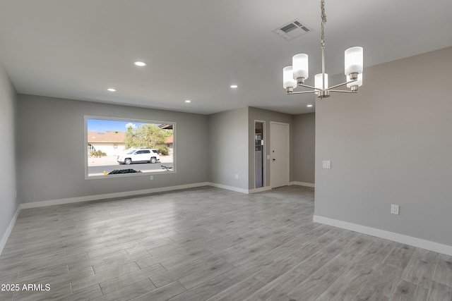 empty room with baseboards, visible vents, wood finished floors, a chandelier, and recessed lighting