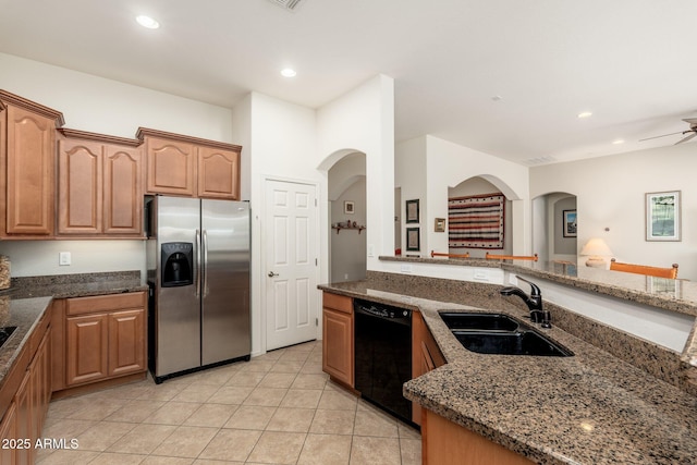 kitchen with dishwasher, sink, dark stone countertops, stainless steel fridge, and light tile patterned floors