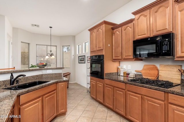 kitchen with sink, a chandelier, hanging light fixtures, dark stone countertops, and black appliances