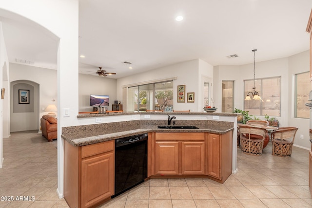 kitchen with ceiling fan with notable chandelier, pendant lighting, dishwasher, sink, and dark stone counters