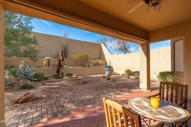 view of patio / terrace featuring area for grilling, ceiling fan, and a fire pit