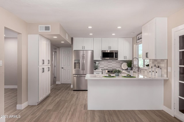 kitchen featuring light countertops, visible vents, appliances with stainless steel finishes, white cabinets, and a peninsula