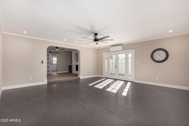 unfurnished living room featuring arched walkways, a wall unit AC, a barn door, ceiling fan, and baseboards